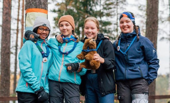 Four happy girl scouts outdoors in Finland