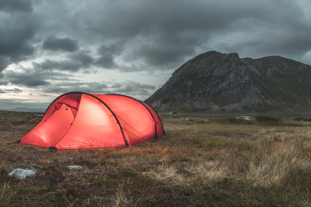 Punainen teltta illalla Lofooteilla rannassa pystyssä. 