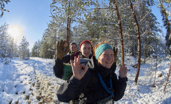 Kolme partiolaista suunnistaa talvisessa metsässä