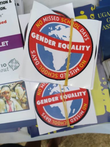 Projektin logosta teetettyjä tarroja, joissa on maapallon kuva, jonka ympärillä teksti No Missed School Days sekä keskellä teksti gender equality.