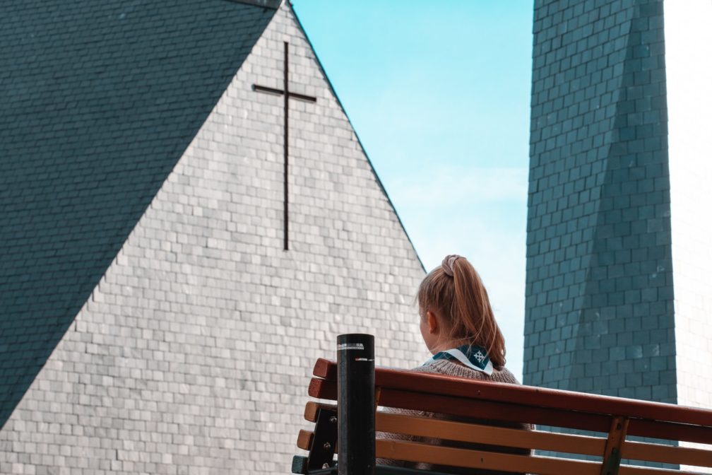 Huivikaulainen tyttö istuu kirkon edessä.