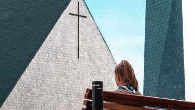 Huivikaulainen tyttö istuu kirkon edessä.