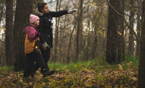 Aikuinen ja lapsi kulkevat yhdessä metsässä